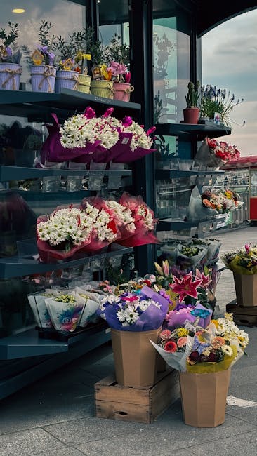 A display of various floral arrangements at Dalston Florist, including bouquets of white chrysanthemums wrapped in pink paper, pink and purple flowers in tissue paper, and colorful mixed bouquets in b